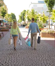 Par med shoppingkassar promenerar bort längs gågatan i Mariehamn.