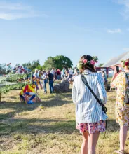 Kvinna fotograferar lövning av stången vid midsommarfirande på Bergö.