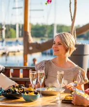 Kvinnor äter middag i kvällssolen vid restaurang ÅSS Paviljongen i Mariehamns västra hamn.