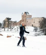 Kvinna skidar på golfbanan med Kastelholms slott i bakgrunden.