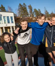 Träningskompisar poserar framför Baltic friidrottsarena i Mariehamn.