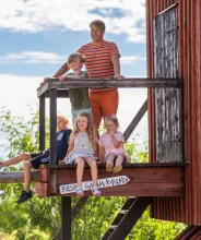En man och fyra barn vid en röd kvarn på ett somrigt Åland.