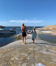 Pojke och flicka går hand i hand över klipporna på en ö i den åländska skärgården.
