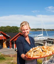 Värdinnan Anette Gustafsson med ett fat nybakade bullar vid gästhamnen Rödhamn på Åland.