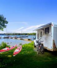 Campingplats vid havet med husbil, kajaker, cyklar och gästbrygga.