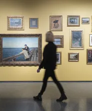 Kvinna tittar på tavlor i utställning vid Ålands konstmuseum.