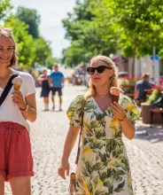 Kvinnor äter glass och promenerar på gågatan i Mariehamn.