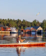 Kvinna som paddlar kajak vid fiskeläget i Käringsund.