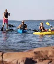 Barn och vuxna som paddlar kajak och SUP på Åland.