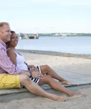 Par sitter på trägången vid Lilla holmens badstrand.