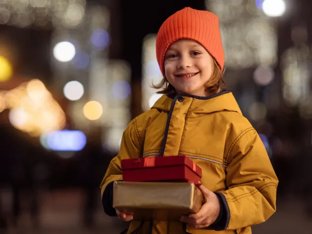 Leende barn i ytterkläder med två paket i händerna.