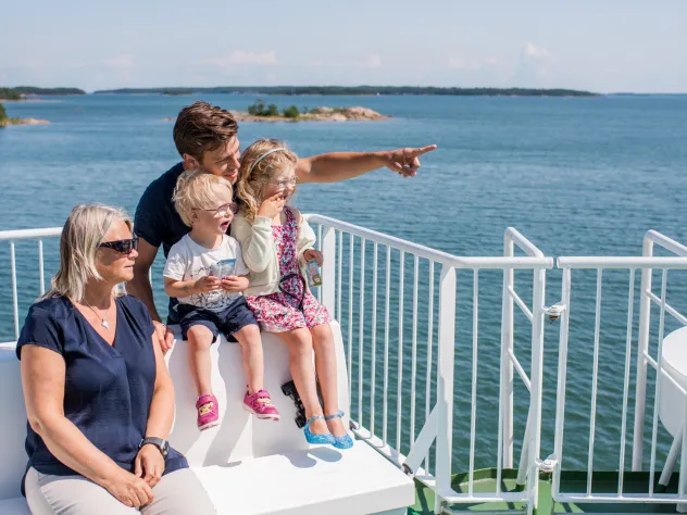 Familj med farmor, pappa och två barn på soldäcket på åländsk skärgårdsfärja.