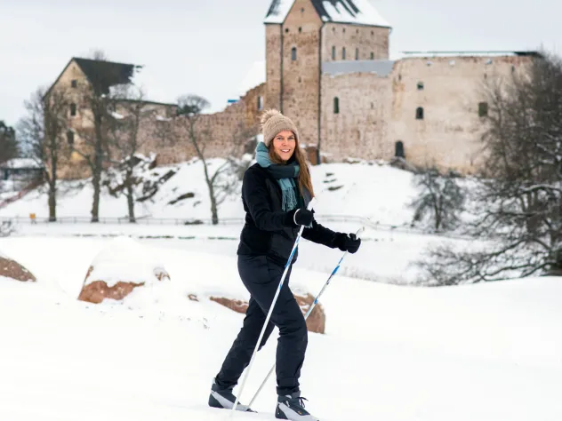 Kvinna skidar på golfbanan med Kastelholms slott i bakgrunden.