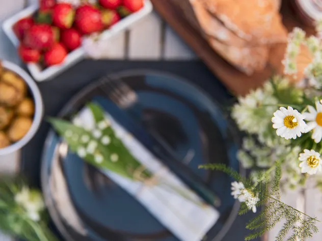 Midsommardukning med nypotatis, jordgubbar och prästkragar.