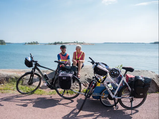 Cyklister på cykelsemester sitter och vilar på en klippa vid havet på Åland.