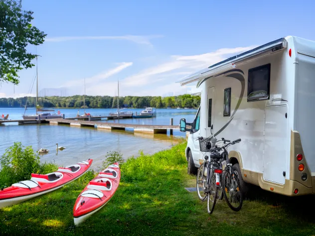 Campingplats vid havet med husbil, kajaker, cyklar och gästbrygga.