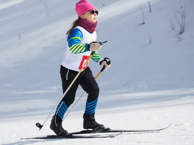 Flicka som deltar i skidtävling på längdskidor.