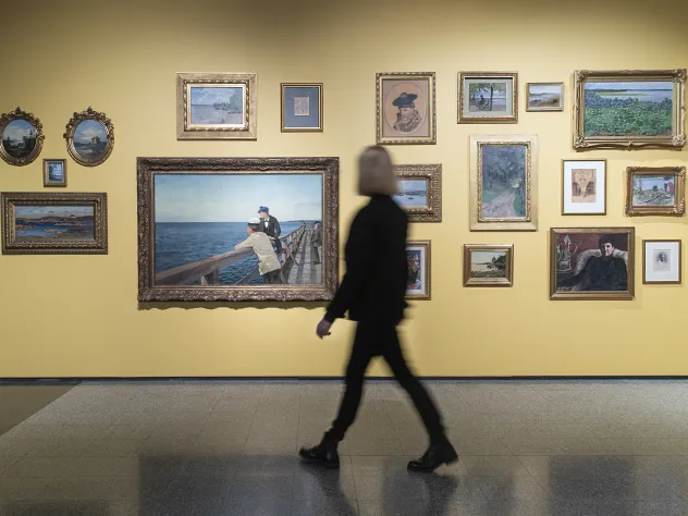 Kvinna tittar på tavlor i utställning vid Ålands konstmuseum.