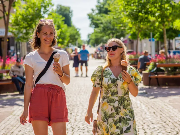 Kvinnor äter glass och promenerar på gågatan i Mariehamn.