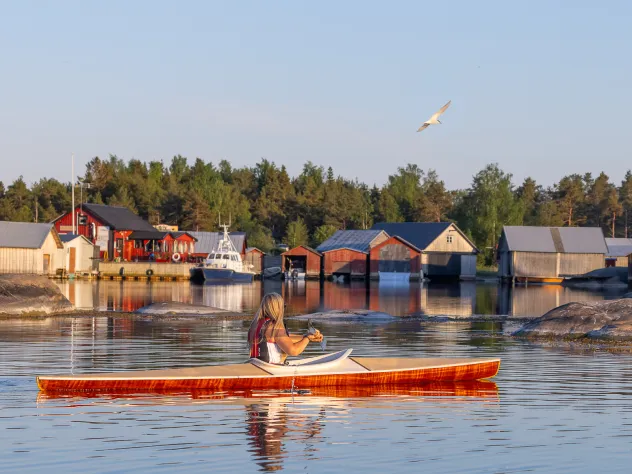 Kvinna som paddlar kajak vid fiskeläget i Käringsund.