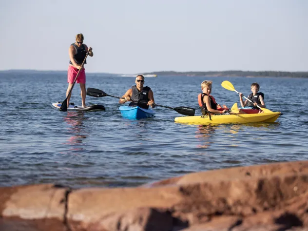 Barn och vuxna som paddlar kajak och SUP på Åland.