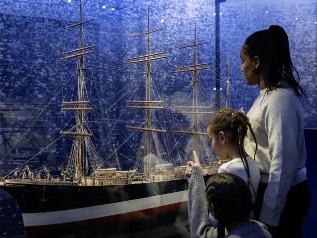 Familj tittar på fartygsmodellen av fartyget Ponape vid Ålands sjöfartsmuseum.