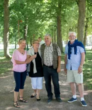 Fyra pensionärer på promenad i den lummiga lindallén i Mariehamn.