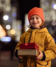 Leende barn i ytterkläder med två paket i händerna.