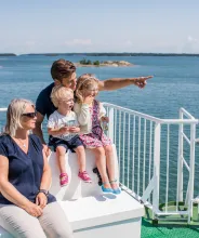 Familj med farmor, pappa och två barn på soldäcket på åländsk skärgårdsfärja.