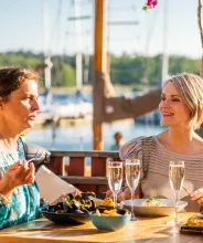 Kvinnor äter middag i kvällssolen vid restaurang ÅSS Paviljongen i Mariehamns västra hamn.