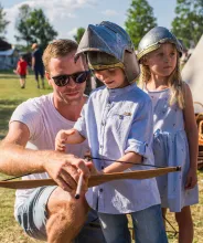 Barn med förälder spänner pilbåge på Vikingamarknaden i Kvarnbo.