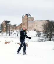 Kvinna skidar på golfbanan med Kastelholms slott i bakgrunden.