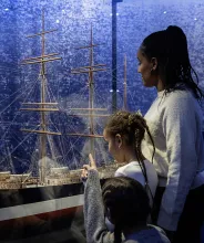Familj tittar på fartygsmodellen av fartyget Ponape vid Ålands sjöfartsmuseum.