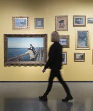 Kvinna tittar på tavlor i utställning vid Ålands konstmuseum.