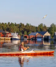 Kvinna som paddlar kajak vid fiskeläget i Käringsund.