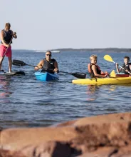 Barn och vuxna som paddlar kajak och SUP på Åland.