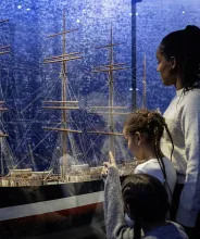 Familj tittar på fartygsmodellen av fartyget Ponape vid Ålands sjöfartsmuseum.