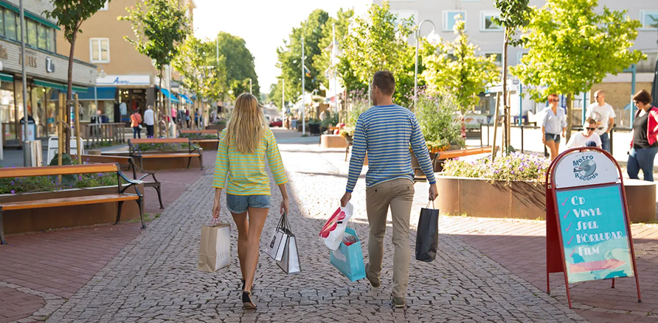 Par med shoppingkassar promenerar bort längs gågatan i Mariehamn.