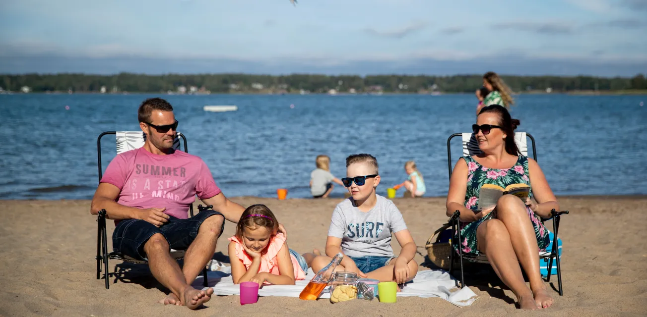 Barnfamilj på sandstranden vid Lilla Holmen.