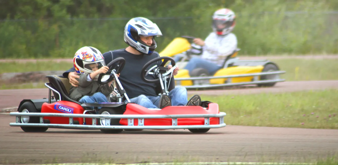 Barn och vuxen kör gokart tillsammans.