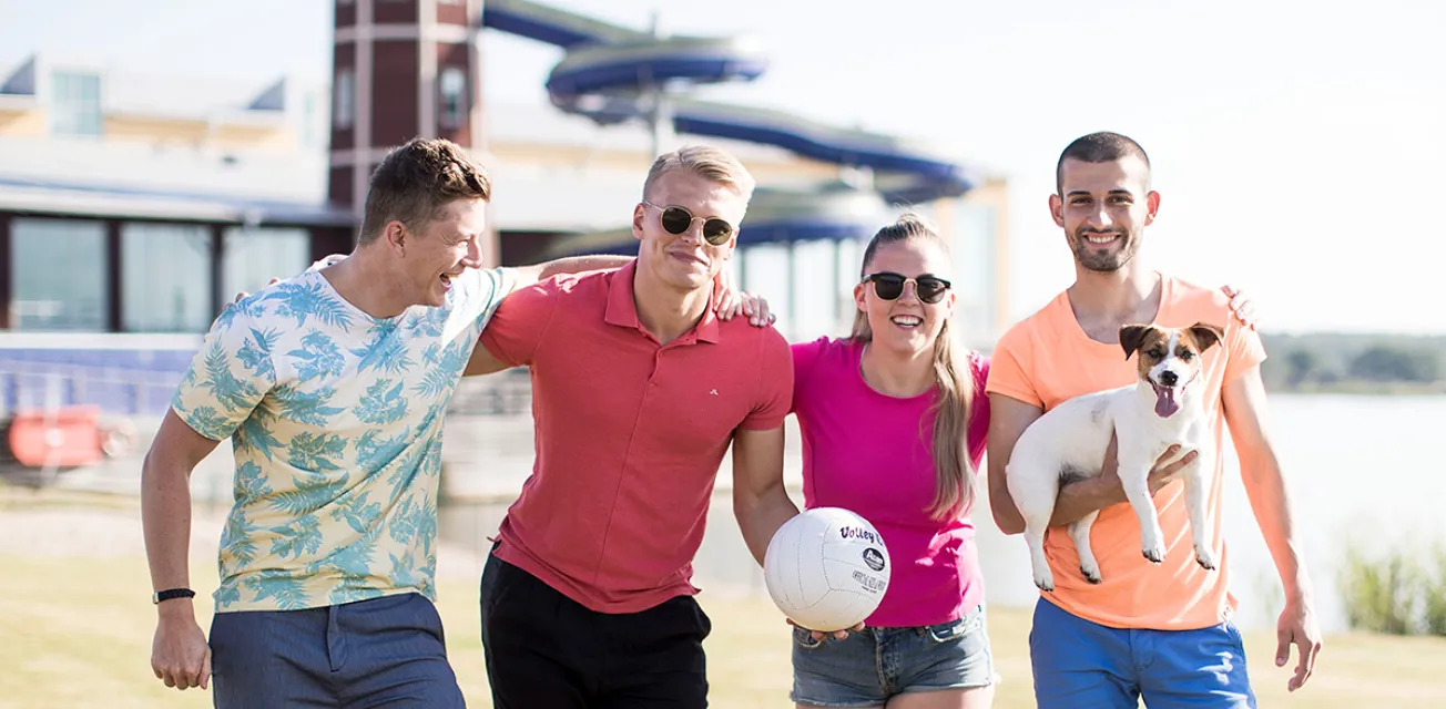 Sportiga ungdomar poserar med beachvolleyboll framför badhuset Mariebad.