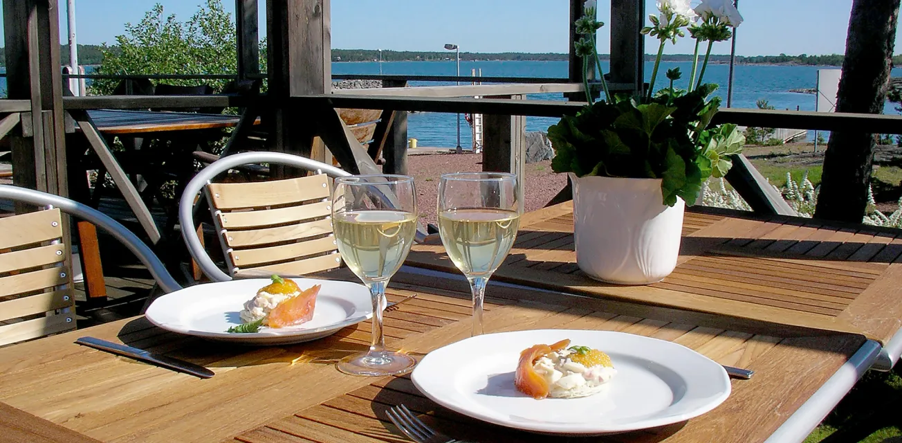 Vy mot vattnet från dukat bord vid restaurang Glada Laxens uteservering.