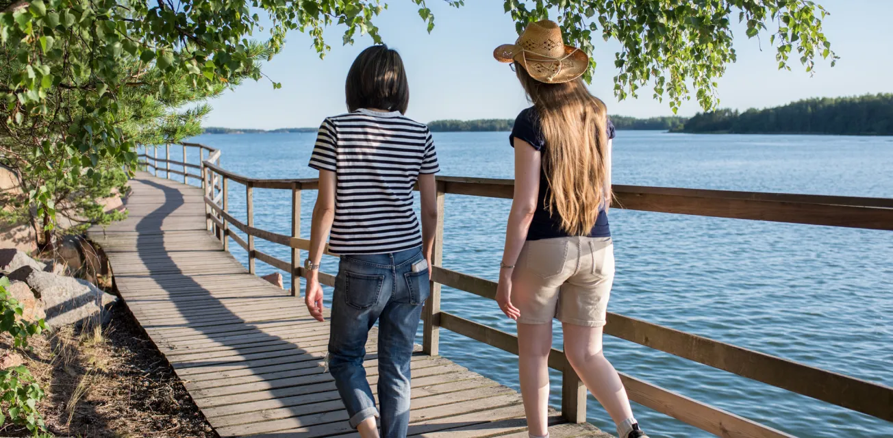 Två kvinnor promenerar längst strandpromenaden i Mariehamn.