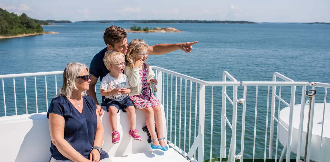 Familj med farmor, pappa och två barn på soldäcket på åländsk skärgårdsfärja.