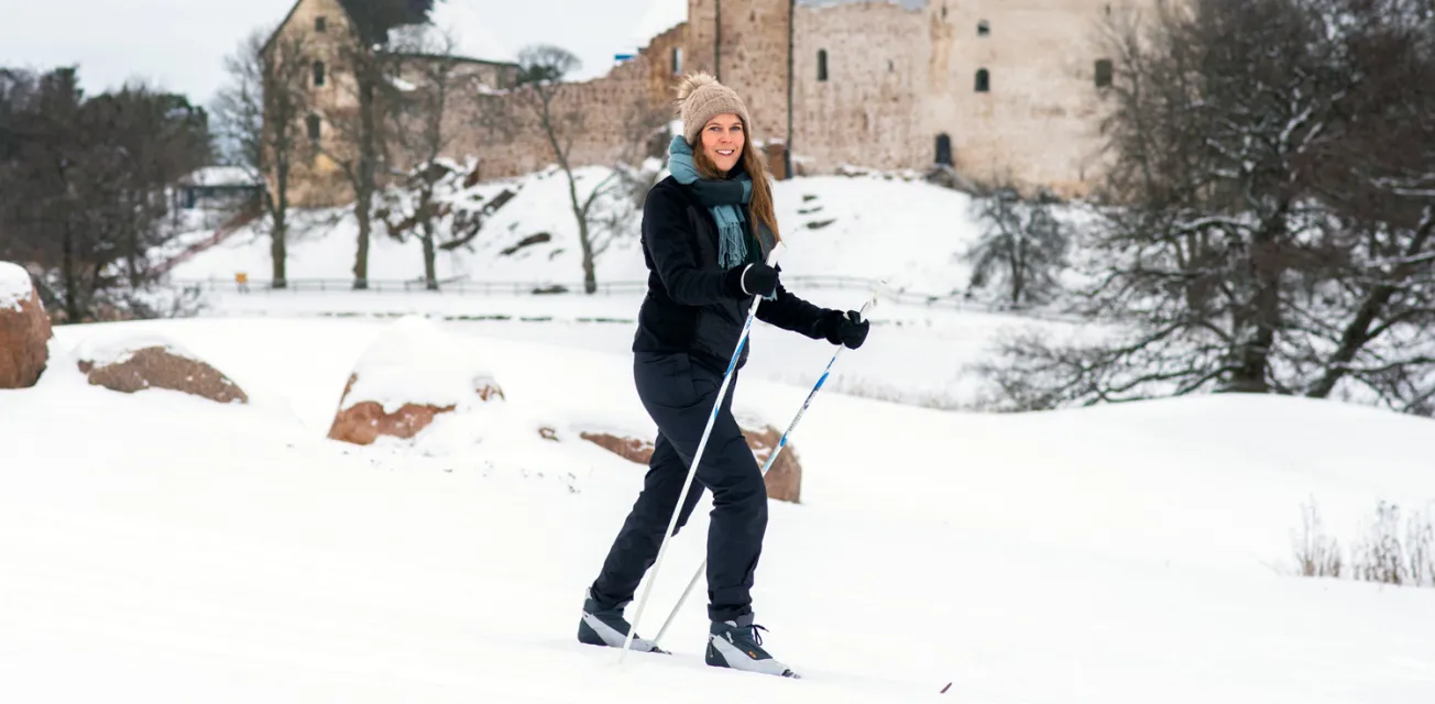 Kvinna skidar på golfbanan med Kastelholms slott i bakgrunden.