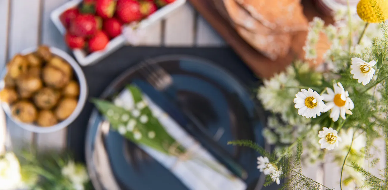 Midsommardukning med nypotatis, jordgubbar och prästkragar.