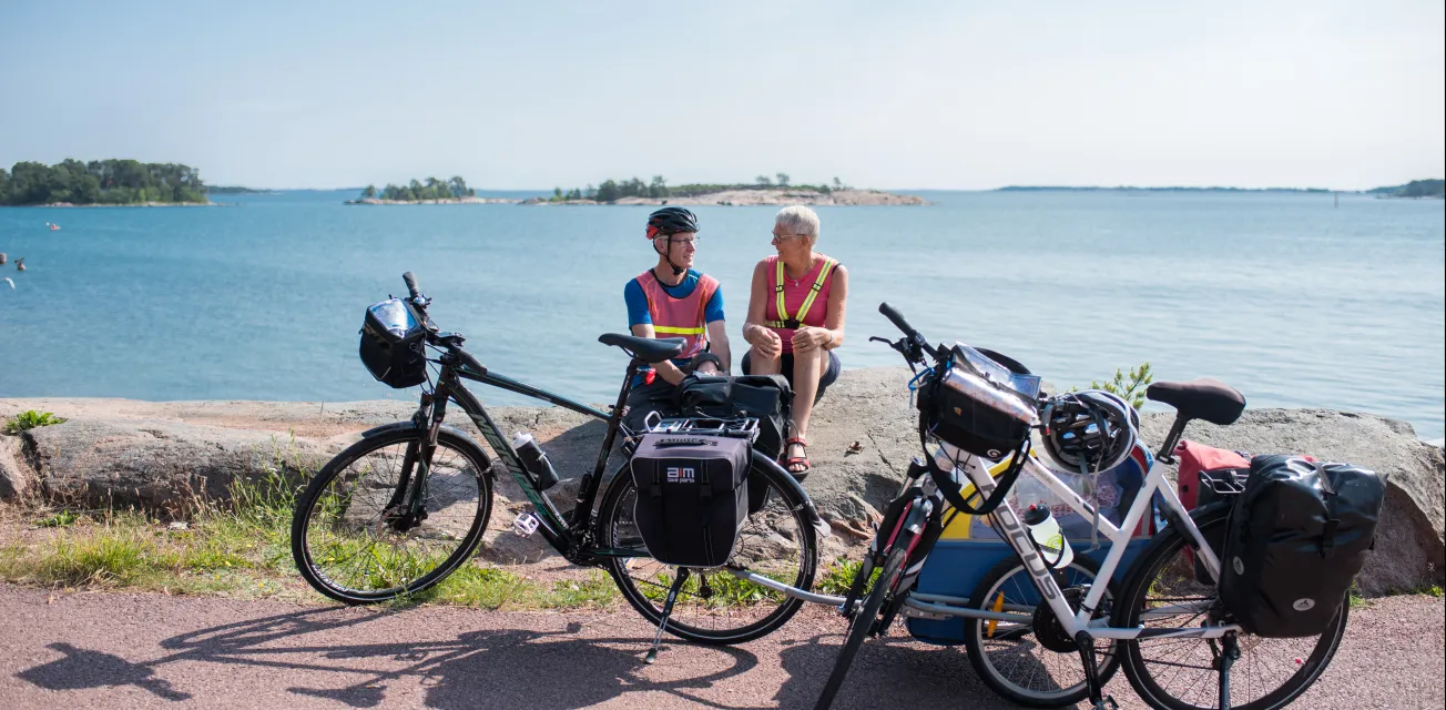 Cyklister på cykelsemester sitter och vilar på en klippa vid havet på Åland.