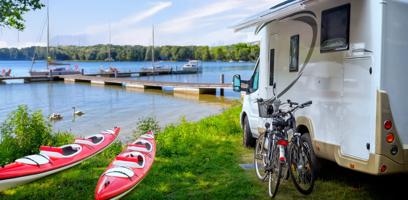Campingplats vid havet med husbil, kajaker, cyklar och gästbrygga.