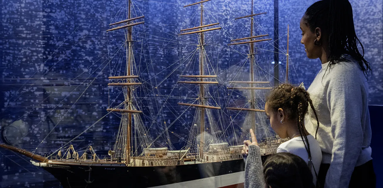 Familj tittar på fartygsmodellen av fartyget Ponape vid Ålands sjöfartsmuseum.