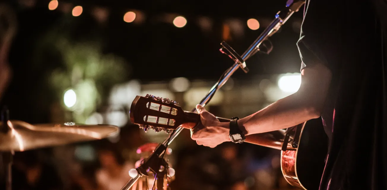 Musikerna spelar rockmusik på scenen, det är en publik full av människor som tittar på konserten.